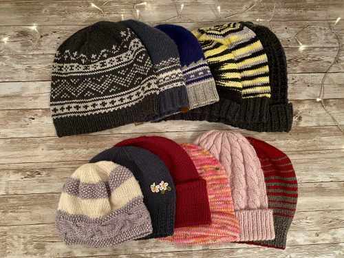 12 knitted heads on a wooden surface