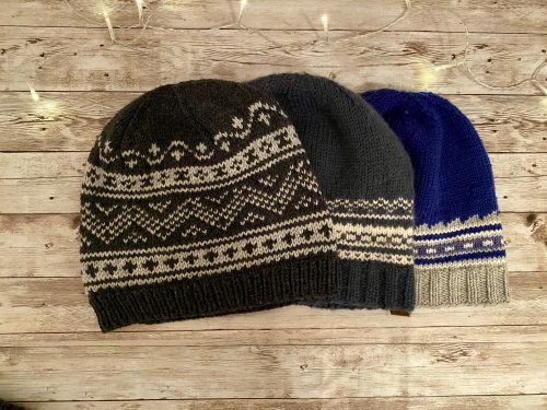 Three knitted hats on a wooden surface