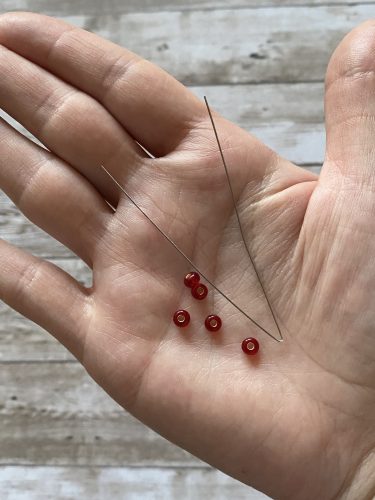 Step-by-step tutorial image demonstrating one of three techniques for threading beads onto yarn for knitting: using a hook, dental floss or thread, or pre-threading. The image shows the tools, materials, and process clearly to guide the viewer through the technique.