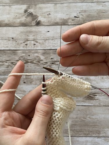Step-by-step tutorial image demonstrating one of three techniques for threading beads onto yarn for knitting: using a hook, dental floss or thread, or pre-threading. The image shows the tools, materials, and process clearly to guide the viewer through the technique.