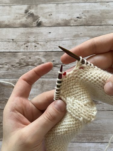 Step-by-step tutorial image demonstrating one of three techniques for threading beads onto yarn for knitting: using a hook, dental floss or thread, or pre-threading. The image shows the tools, materials, and process clearly to guide the viewer through the technique.