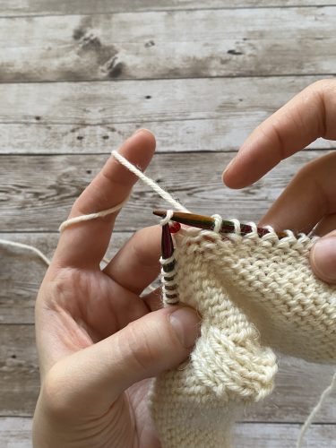 Step-by-step tutorial image demonstrating one of three techniques for threading beads onto yarn for knitting: using a hook, dental floss or thread, or pre-threading. The image shows the tools, materials, and process clearly to guide the viewer through the technique.