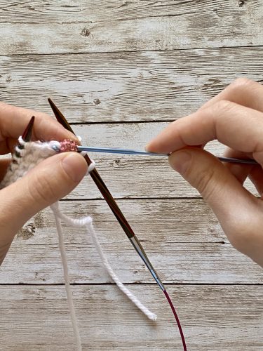 Step-by-step tutorial image demonstrating one of three techniques for threading beads onto yarn for knitting: using a hook, dental floss or thread, or pre-threading. The image shows the tools, materials, and process clearly to guide the viewer through the technique.