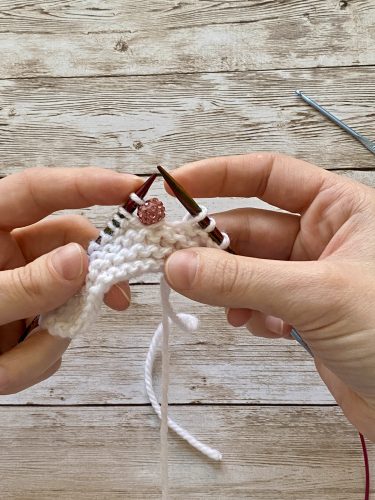 Step-by-step tutorial image demonstrating one of three techniques for threading beads onto yarn for knitting: using a hook, dental floss or thread, or pre-threading. The image shows the tools, materials, and process clearly to guide the viewer through the technique.