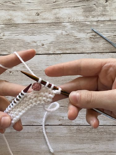 Step-by-step tutorial image demonstrating one of three techniques for threading beads onto yarn for knitting: using a hook, dental floss or thread, or pre-threading. The image shows the tools, materials, and process clearly to guide the viewer through the technique.
