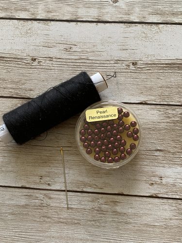 Step-by-step tutorial image demonstrating one of three techniques for threading beads onto yarn for knitting: using a hook, dental floss or thread, or pre-threading. The image shows the tools, materials, and process clearly to guide the viewer through the technique.