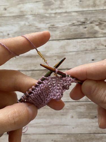 Step-by-step tutorial image demonstrating one of three techniques for threading beads onto yarn for knitting: using a hook, dental floss or thread, or pre-threading. The image shows the tools, materials, and process clearly to guide the viewer through the technique.