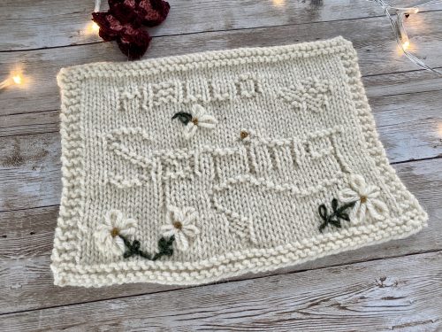Finished Hello Spring Square with embroidered flowers on a wooden surface