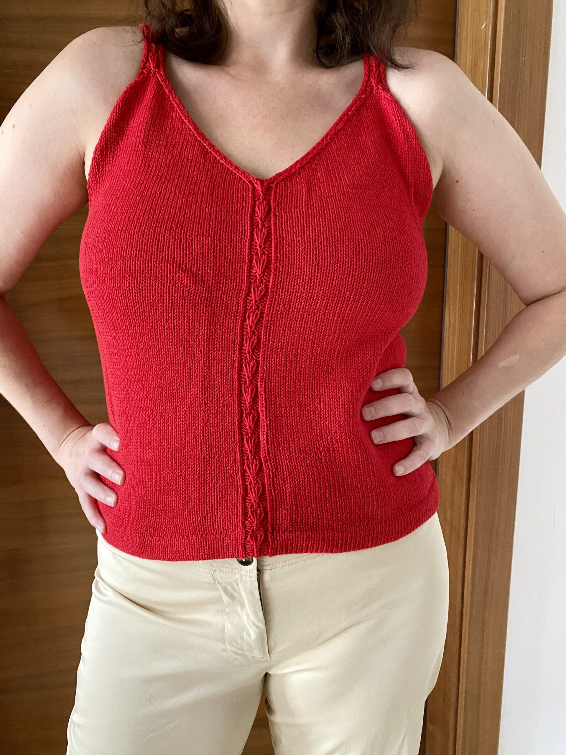 A front view of the Ginkgo Biloba Top, worn by a woman. The sleeveless design with a V-neckline and central lace panel is paired with light beige pants, creating a casual yet stylish look.