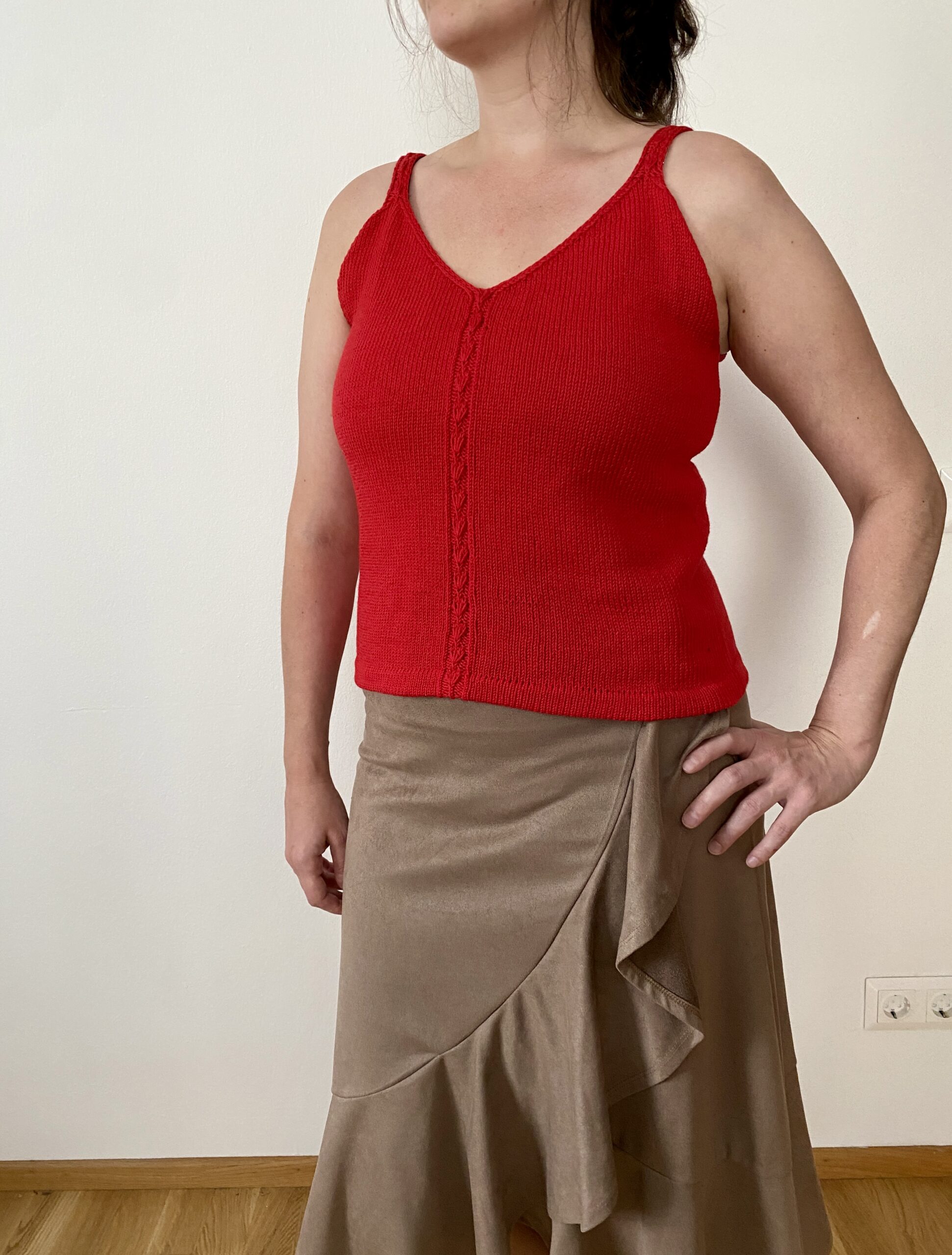 A front view of the Ginkgo Biloba Top, worn by a woman. The sleeveless, fitted design features a V-neckline and a central lace panel, paired with a beige ruffled skirt for a chic and elegant look.