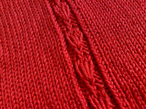 A detailed close-up of the central lace panel of the Ginkgo Biloba Top, highlighting the intricate leaf-like pattern in vibrant red yarn.