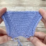 Close-up of hands demonstrating a lifted increase on the purl side.