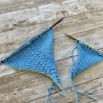 Close-up of two knitted swatches on wooden knitting needles, in blue yarn, showing two knitting techniques.