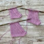 Three swatches of pink knitted fabric are displayed on a wooden surface, each demonstrating the effect of "ssk" (slip, slip, knit) decreases. The swatches are on wooden knitting needles, showing how the stitches slant to the left, creating a neat, angled edge. The yarn tails are visible, and the texture of the stockinette stitch is prominent.