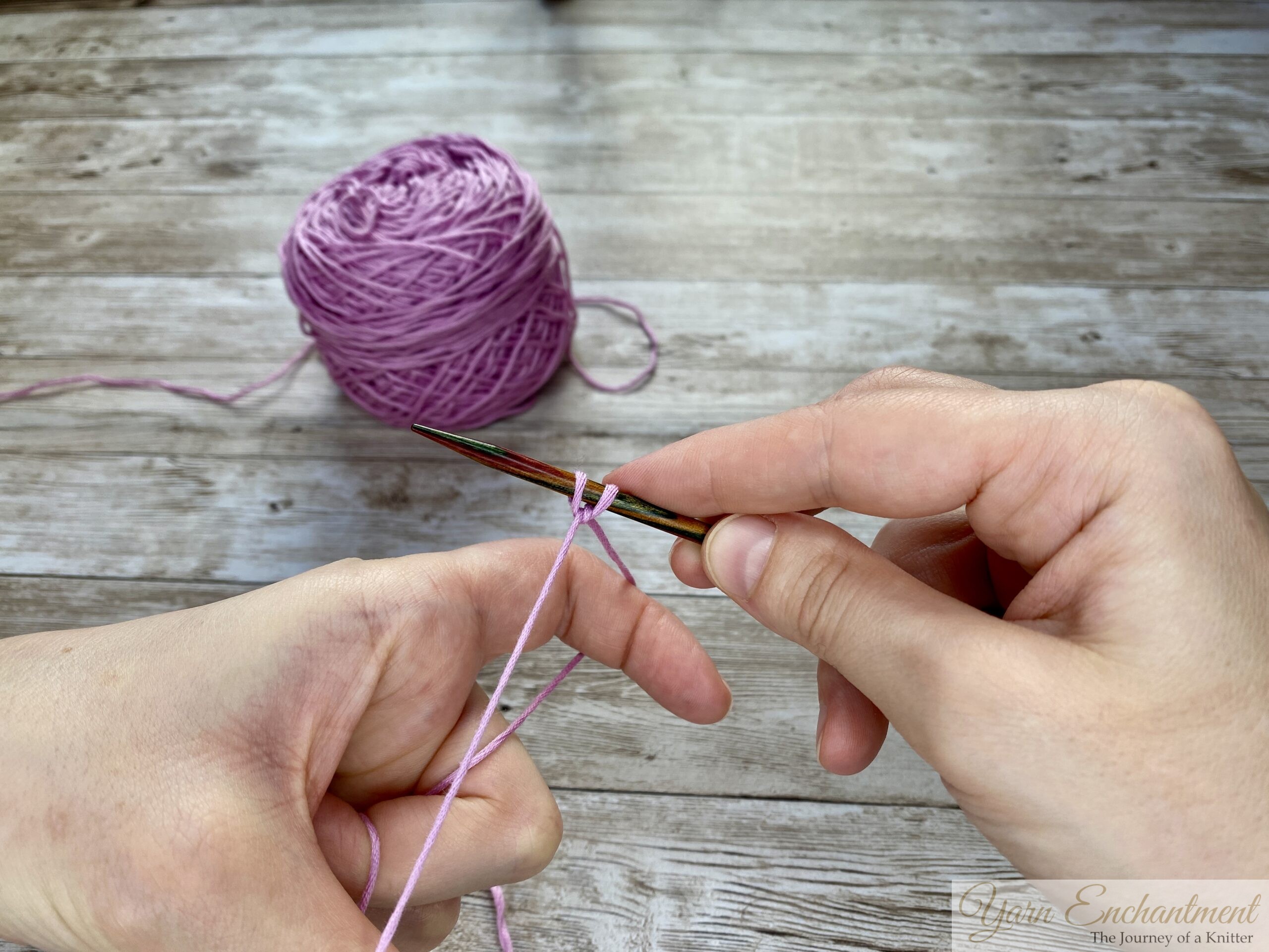 Close-up of hands demonstrating the long tail cast-on technique in knitting