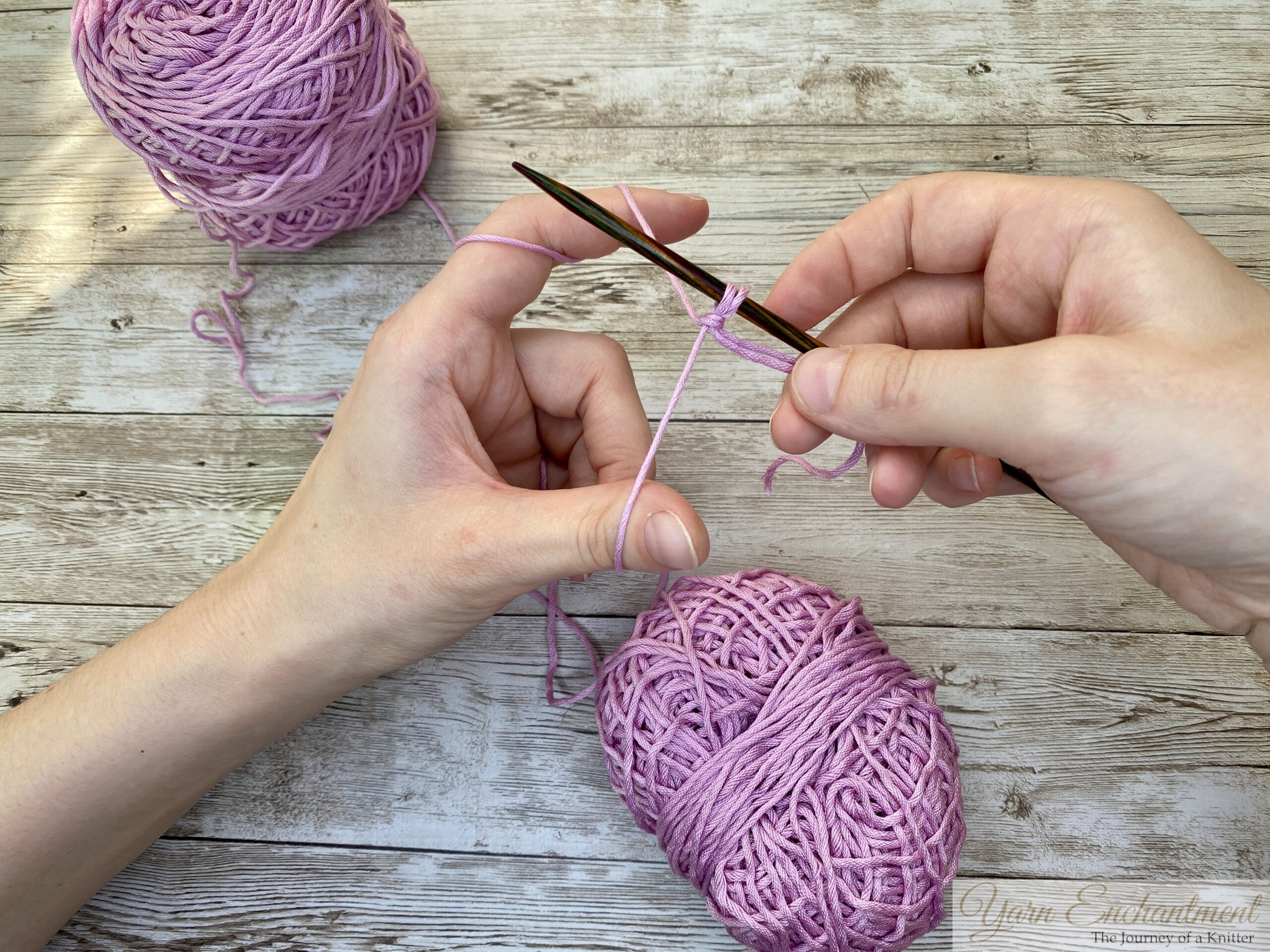 Two strands of pink yarn, one from the inside and one from the outside of a skein, being used for casting on.