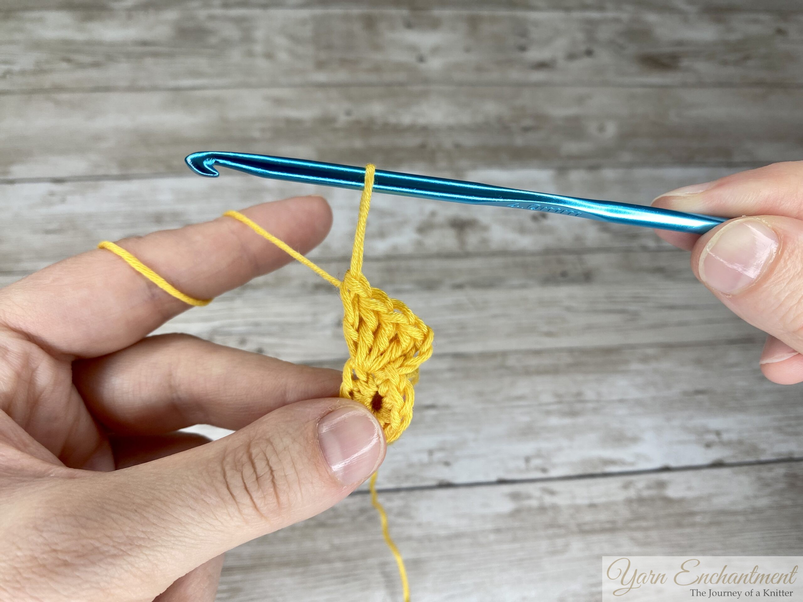 Hand holding a dropped loop of yarn extended loosely from the stitches to prevent unraveling