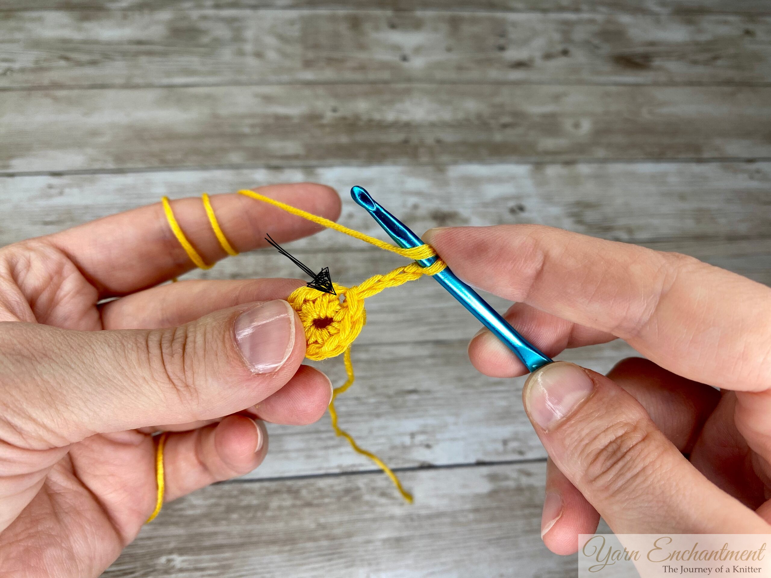 Close-up of a crochet hook chaining 3 stitches with a yellow yarn, preparing for the first double crochet