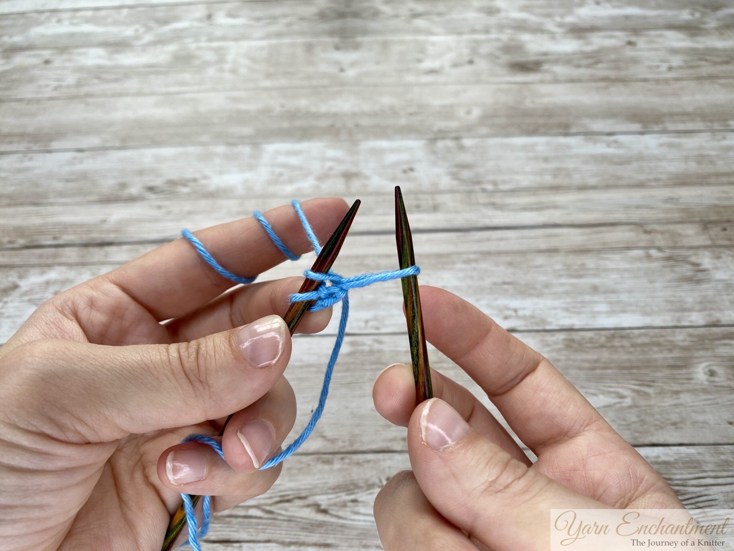 Transferring the newly formed stitch from the right needle to the left needle during a knitted cast-on.
