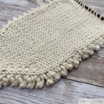 Close-up of a triangular knitted piece with a Picot Edge stitch forming a scalloped border.