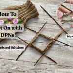 A photo showing a step-by-step knitting tutorial on how to cast on stitches using double-pointed needles (DPNs). In the center, four colorful wooden DPNs form a square with tan yarn cast on, ready for knitting in the round. To the left, a finished piece of ribbed knitting with embroidered pink and purple flowers is visible. Overlay text reads "How To Cast On with DPNs" and "No Twisted Stitches." An inset close-up in the upper right corner highlights how to avoid gaps at the join, with an arrow pointing to the stitches and the label "No Gaps." The background is a light wooden table.