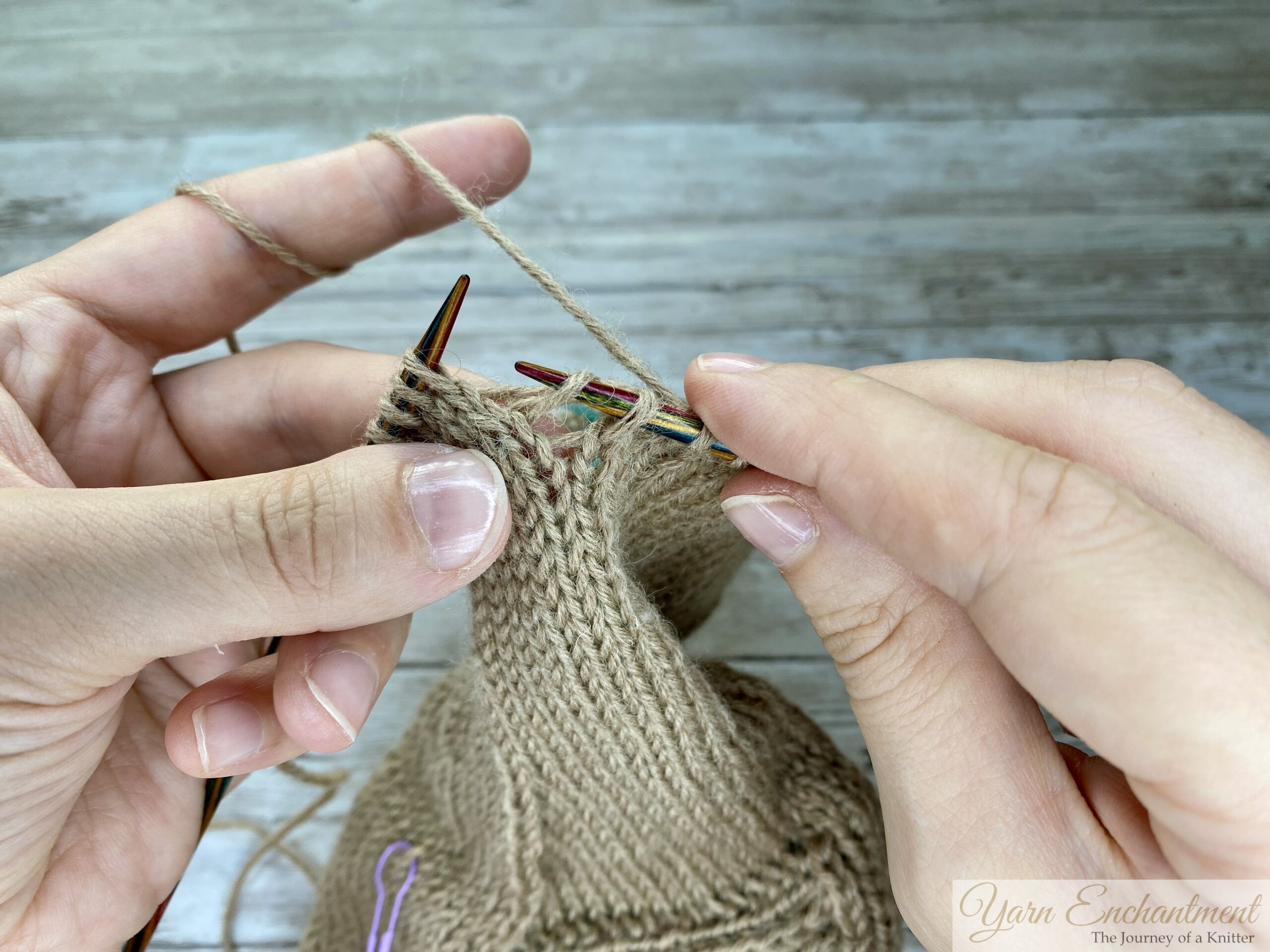 Hands inserting the right knitting needle into the dropped stitch, preparing to lift the first ladder strand through the stitch.