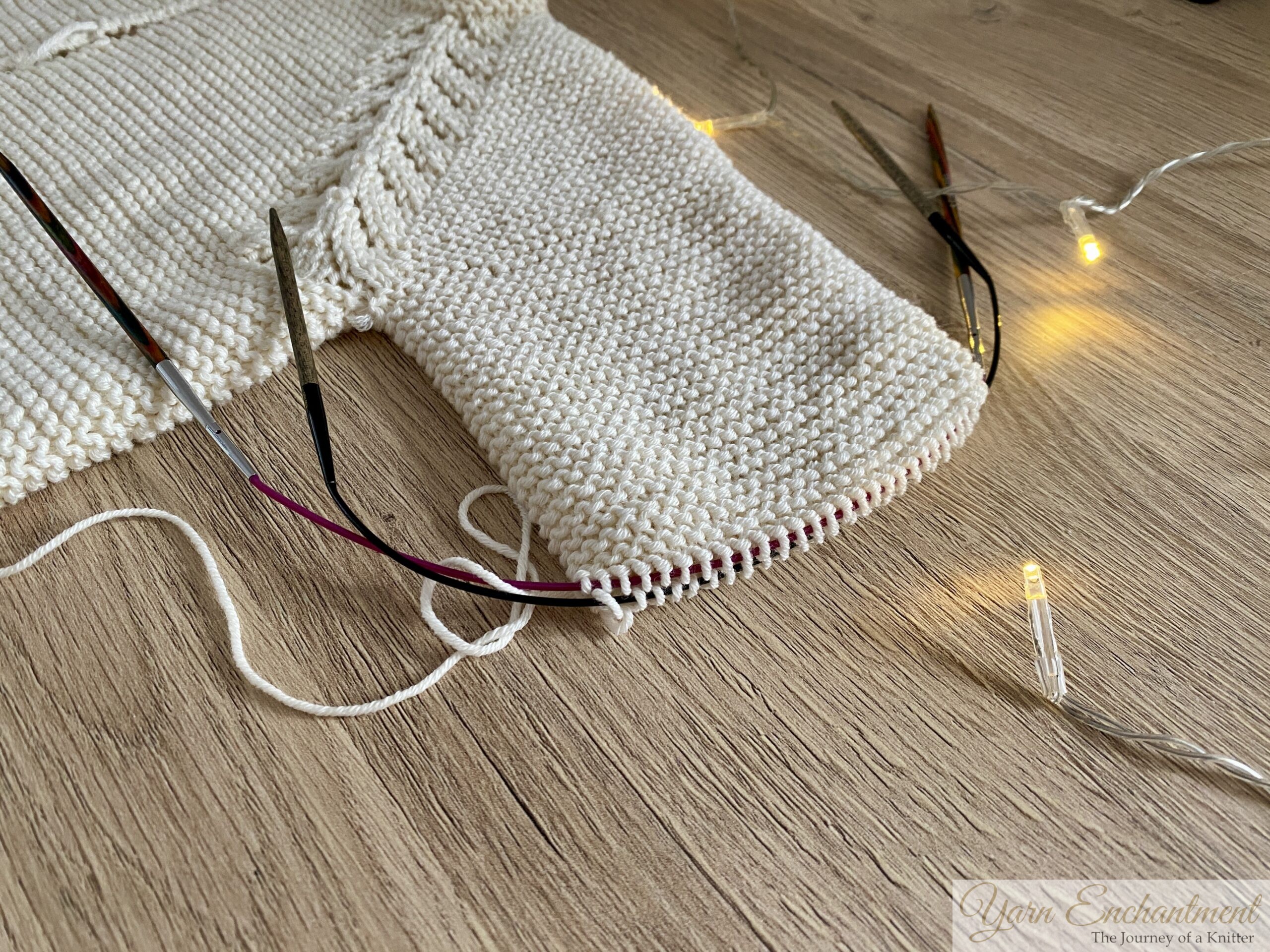 Close-up of unfinished cardigan sleeve with circular knitting needles and yarn, showing technical details and the realities of ongoing knitting projects.