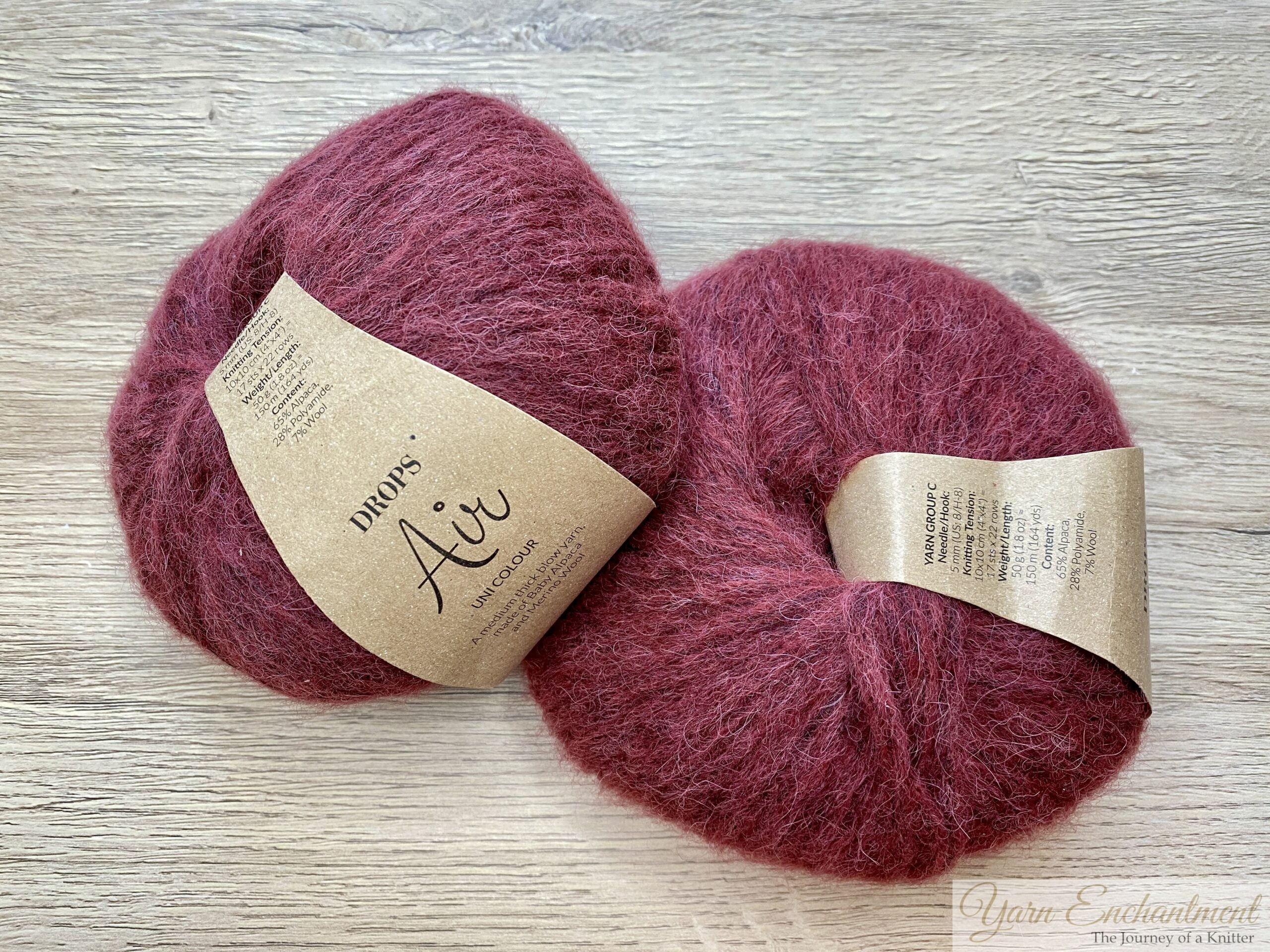 Two skeins of Drops Air yarn in a rich reddish-brown color, shown with their labels on, placed on a light wood surface.