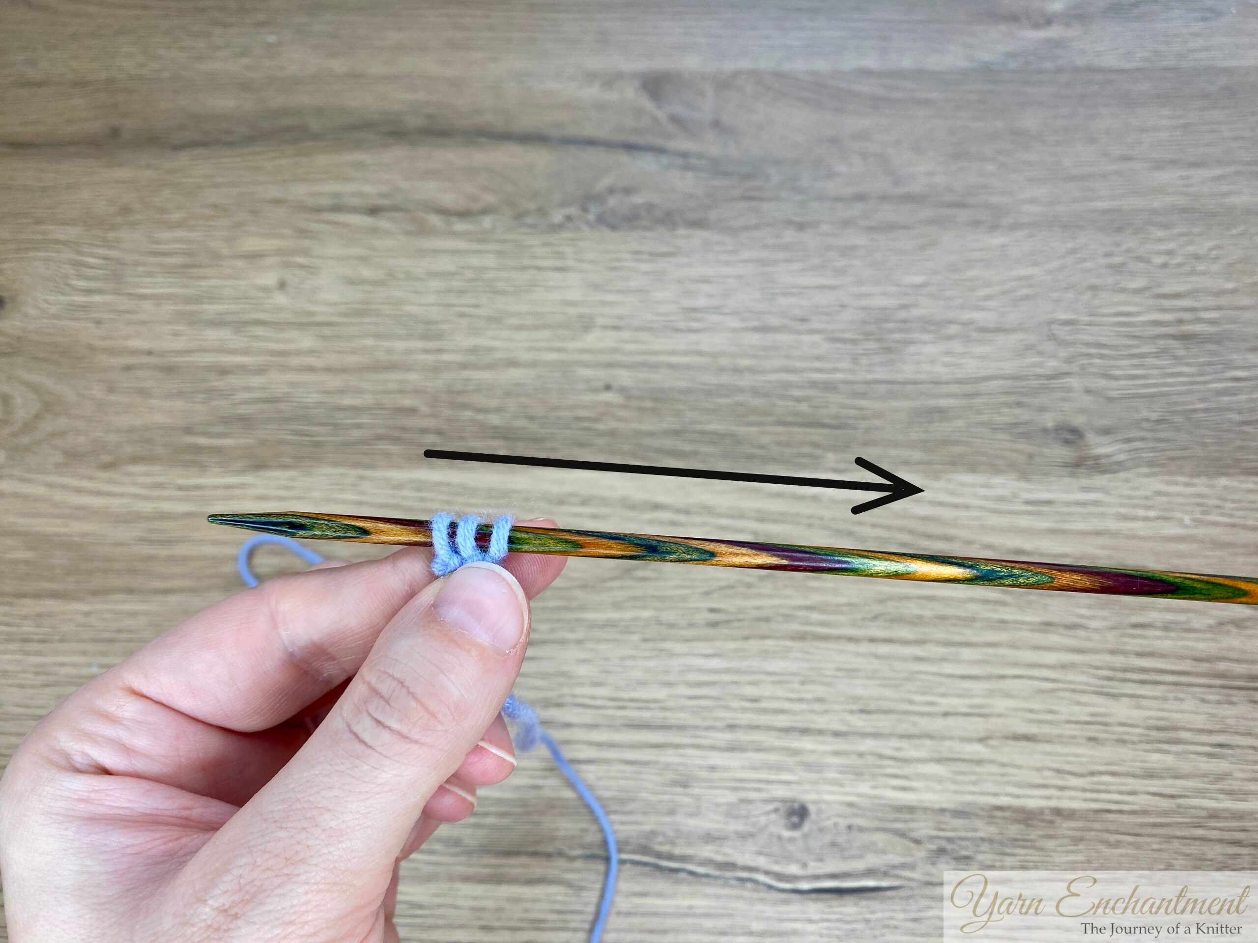 Three stitches of light blue yarn on a wooden needle, shown close-up and centered for a clear view of the stitch setup for i-cord knitting.