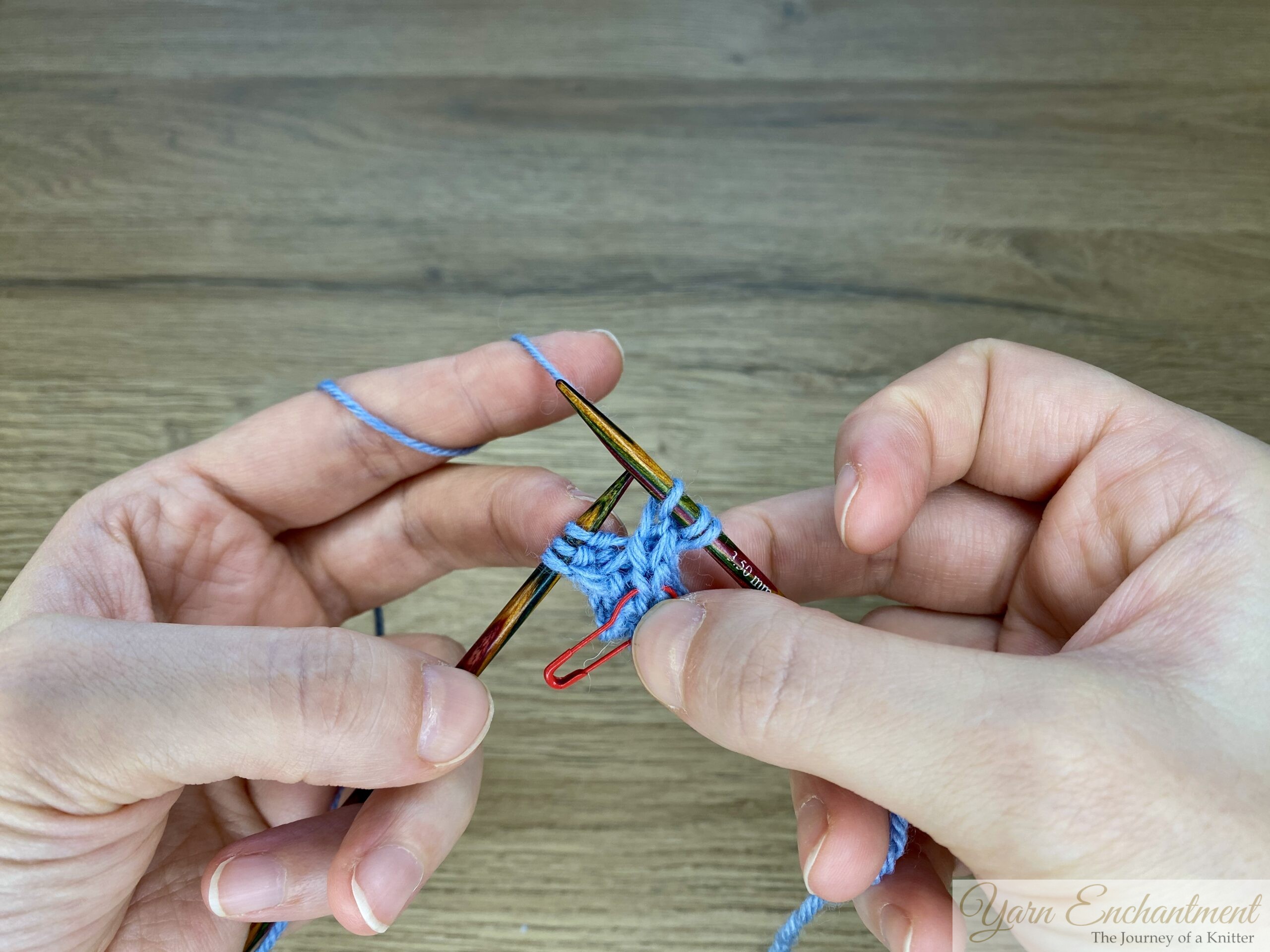 Blue garter-stitch swatch with I-cord edging on wooden needles