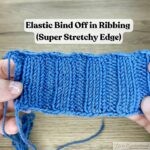 Close‑up of a blue ribbed knitting swatch held in two hands, showing the relaxed elastic bind off edge with a slight flare.