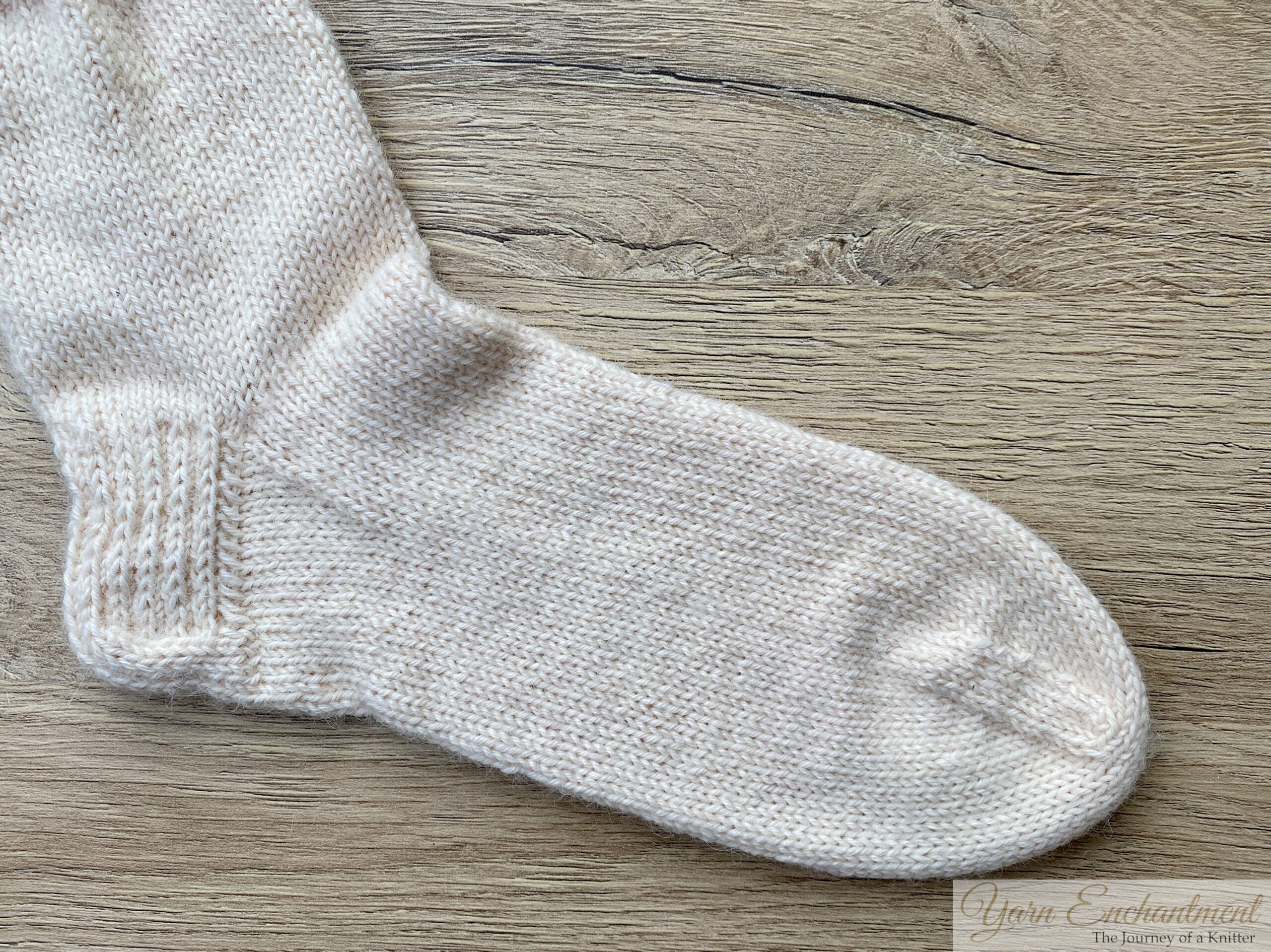 Knitted alpaca sock after blocking, showing even stitch tension and smooth fabric on wood surface