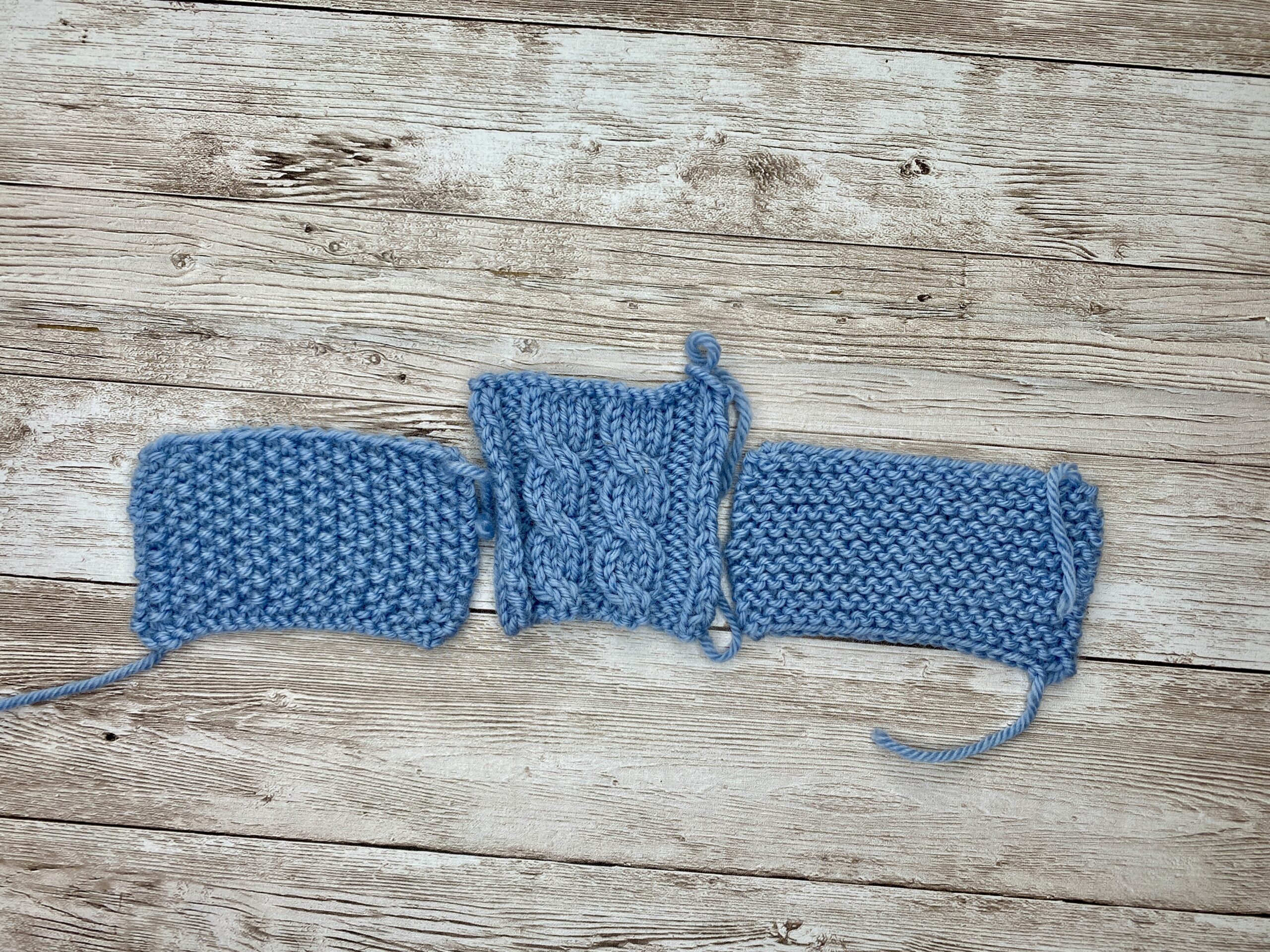 Blue swatch strip showing garter, cable, and garter sections knitted together for border comparison.