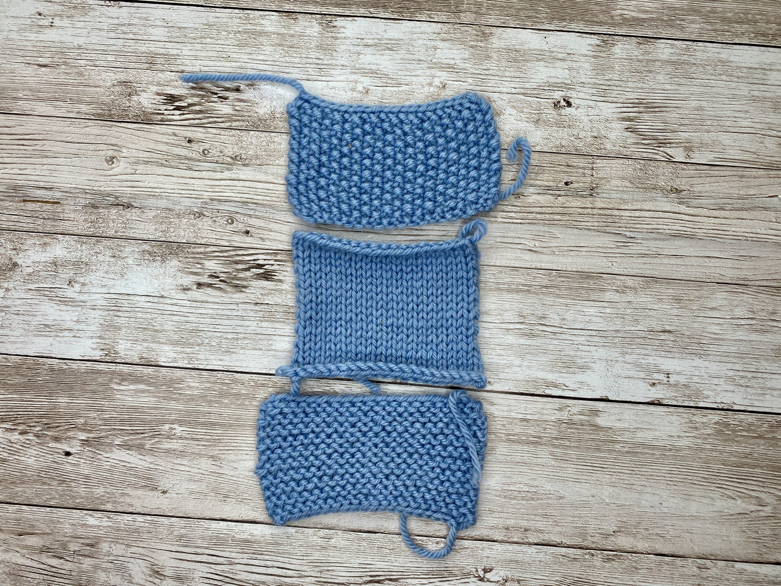 Blue gauge swatch with garter border joined to a borderless blue swatch to compare length and width