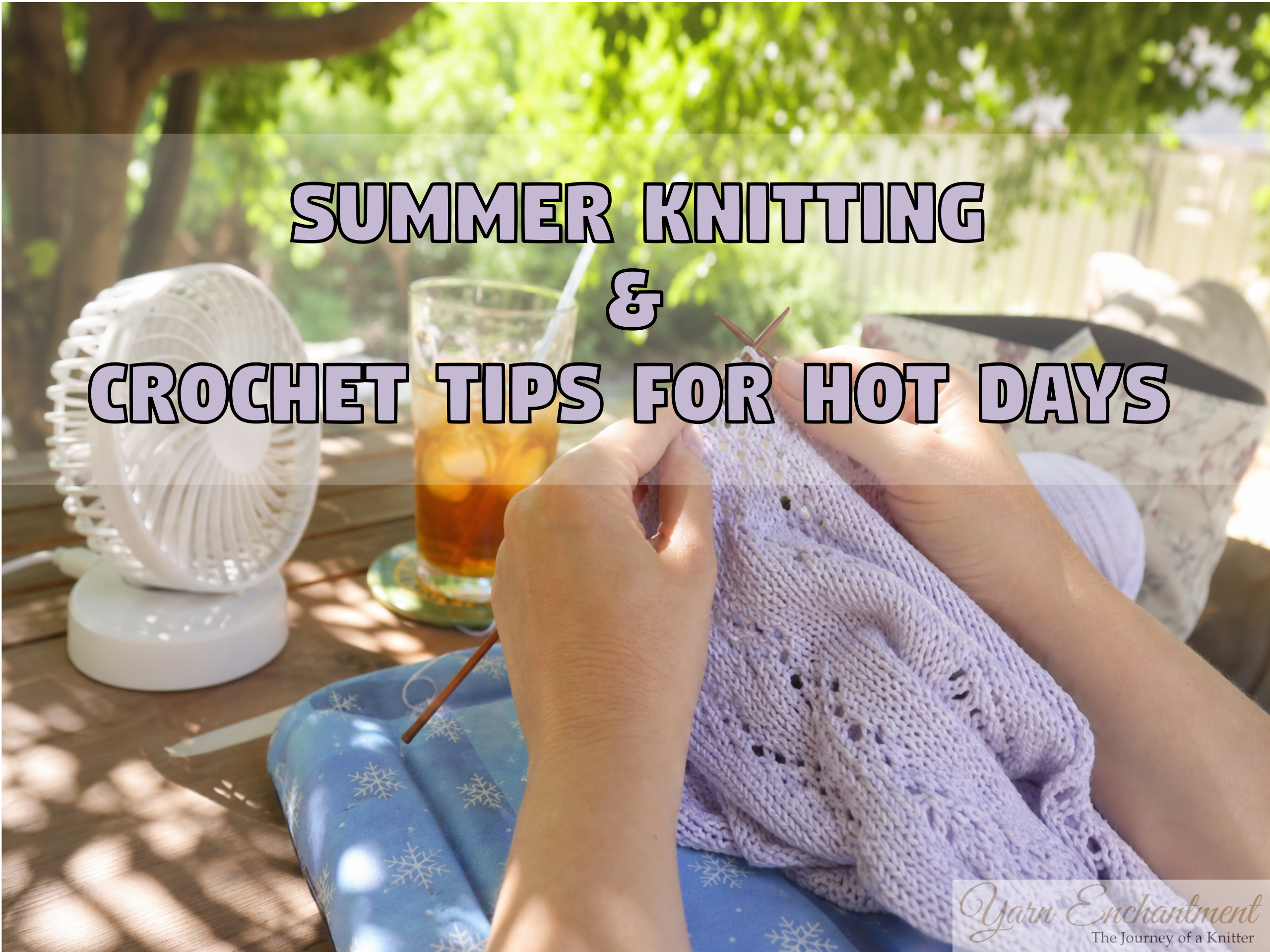 Close-up of hands knitting a light purple lace summer top outdoors. A white portable desk fan and a glass of iced tea sit on a wooden table in the sunny background, illustrating summer knitting and crochet tips for hot days.