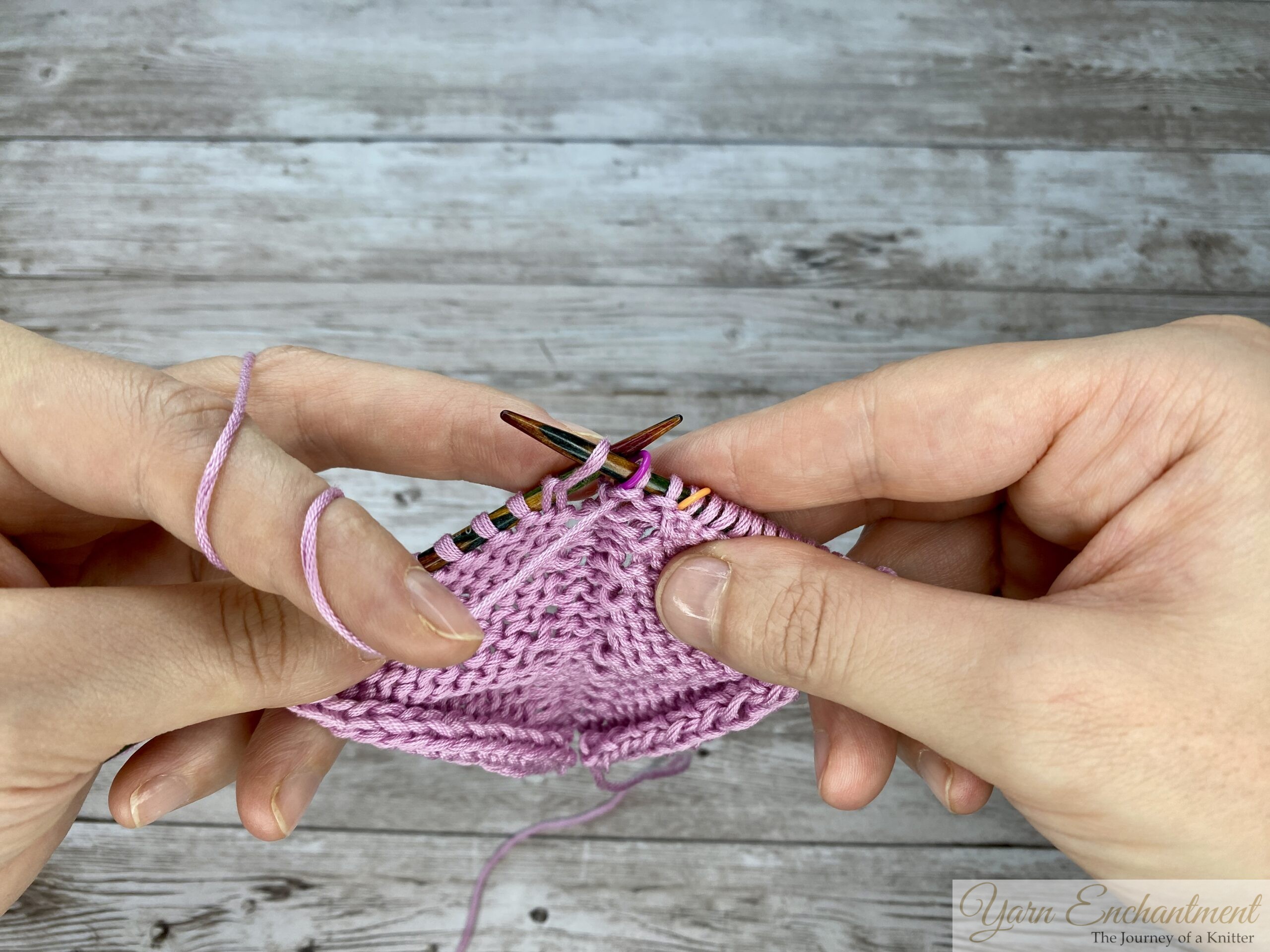 The completed forward yarn-over loop resting on the right needle, ready to be worked, creating an right-leaning increase in a pink in-the-round knitting project.