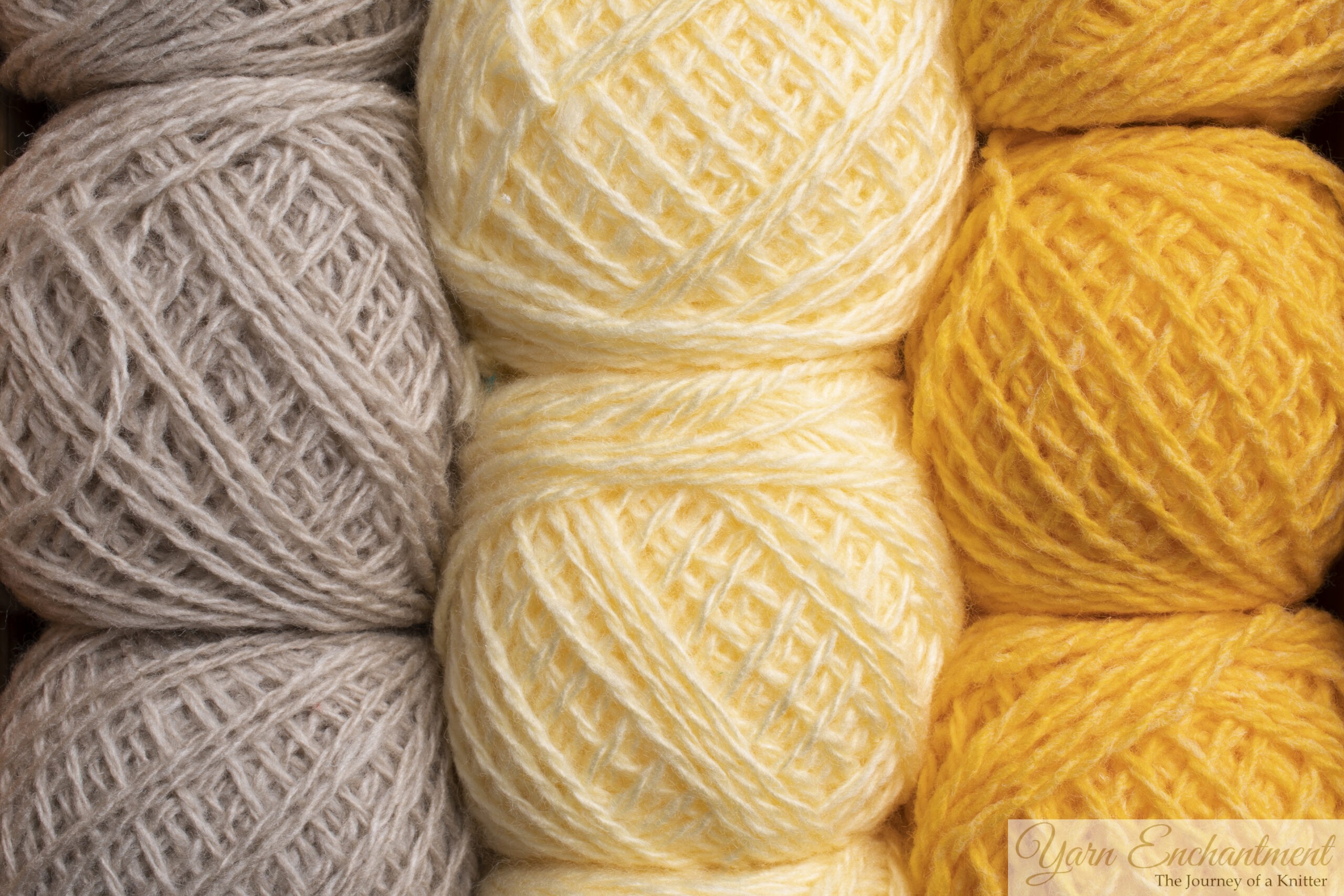 Close-up view of stacked balls of soft yarn in a pastel color palette, featuring a column of light beige, pale buttery yellow, and vibrant golden yellow yarn, showing the crisscross woven texture of the tightly wound strands.