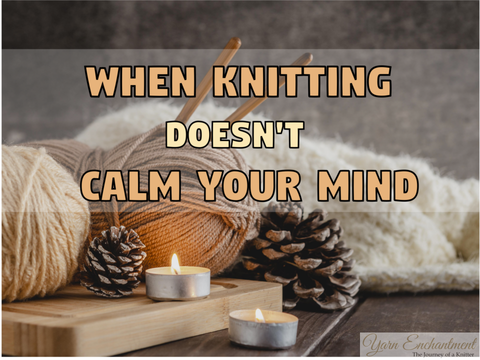 A cozy arrangement of thick tan yarn, wooden knitting needles, a soft white knitted blanket, pinecones, and two lit tealight candles resting on a wooden board, overlaid with the text "WHEN KNITTING DOESN'T CALM YOUR MIND