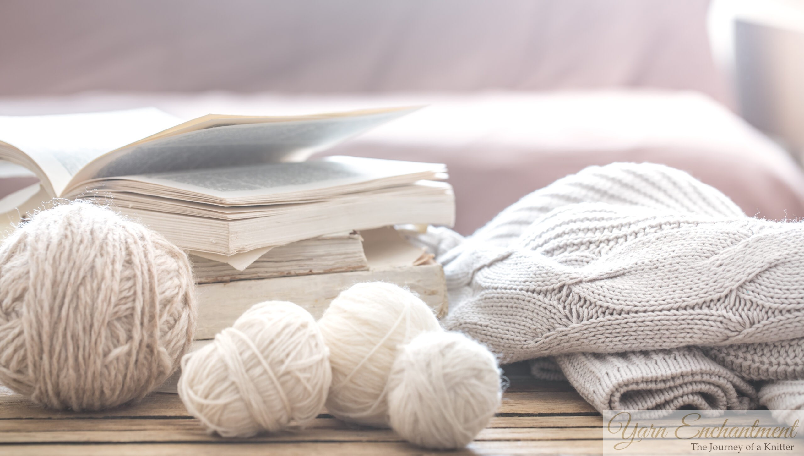 An open book resting on a stack of vintage books beside small balls of cream-colored yarn and a folded, textured knitted sweater, bathed in soft natural sunlight.