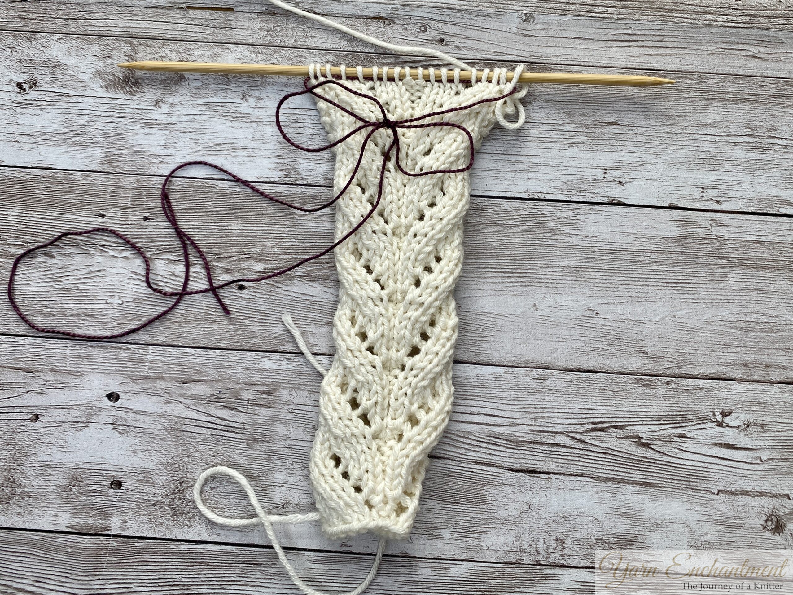 Purple lifeline pulled through a row of cream lace knitting, tail ends tied in a loose bow to keep them in place.