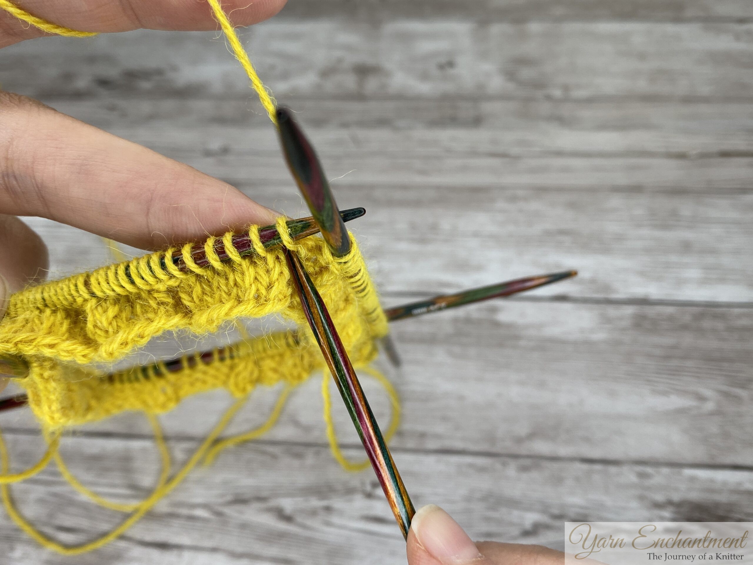 Working a decrease on the yellow ruffle sock cuff on wooden DPNs, round 4 of the ruffle pattern