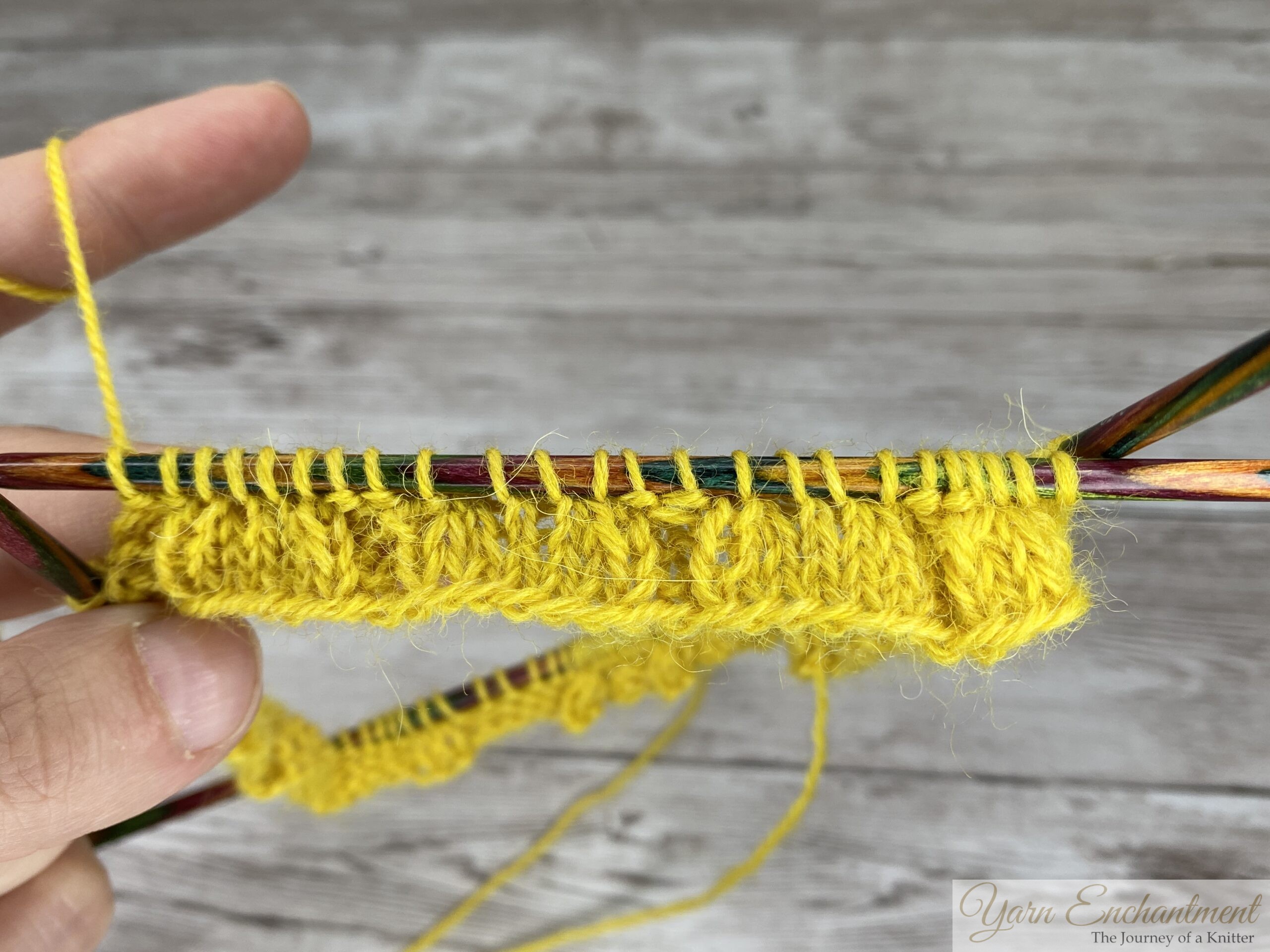 Ruffle sock cuff after the round 4 decreases, showing the paired SSK and K2tog stitches in yellow yarn