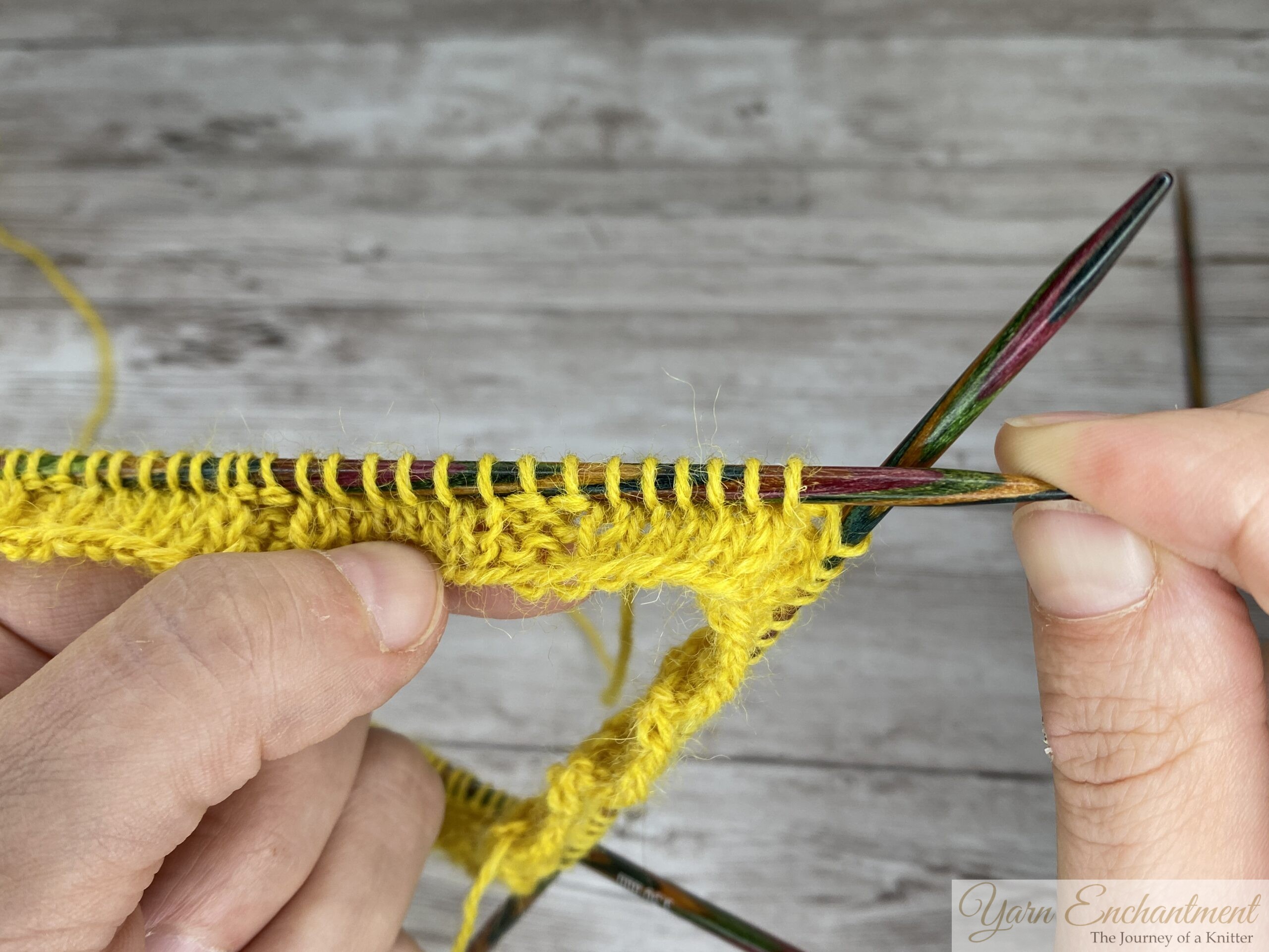Hands knitting the ruffle sock cuff in yellow yarn on wooden DPNs, showing the K6, P2 rib pattern after three rounds