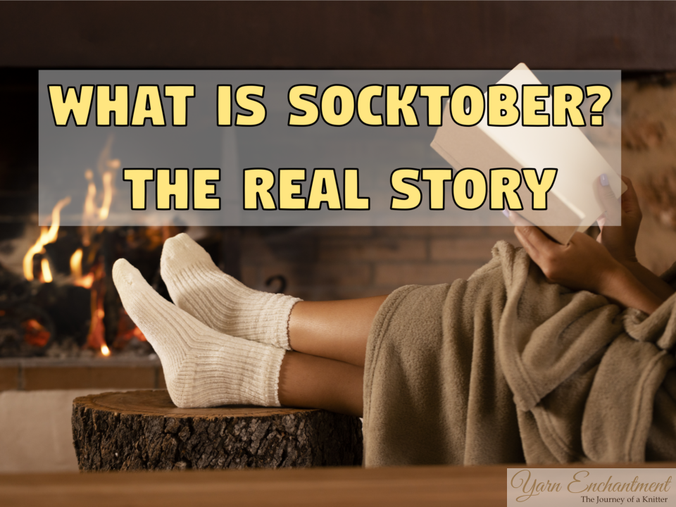 A cozy scene of a person wearing thick cream-colored socks, with their feet propped up on a rustic wooden log in front of a glowing fireplace. The person is wrapped in a soft tan blanket and holding an open book. Large yellow text overlay on a semi-transparent banner reads: WHAT IS SOCKTOBER? THE REAL STORY